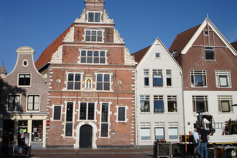 Rij historische bakstenen huizen met trapgevels aan een straat in de binnenstad van Hoorn, met marktkramen